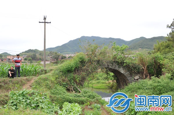 已廢棄的石拱橋，被野草覆蓋，下有溪流，村民稱此路