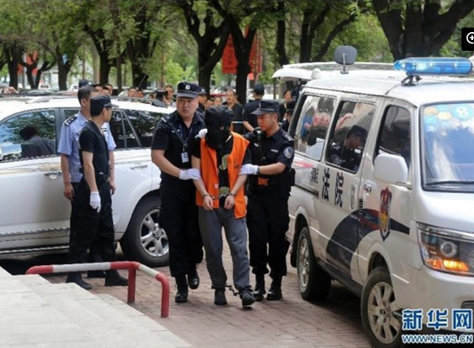 兩名犯罪嫌疑人頭戴面罩，被法警押進(jìn)法庭。