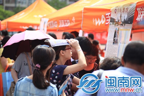 海都咨詢會現(xiàn)場，一名家長頂著烈日看學(xué)校信息