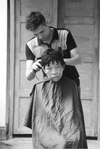 梁江華正在給老人理發(fā)。